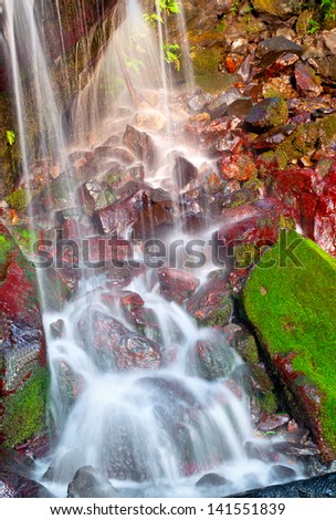 small waterfall falling on red rocks