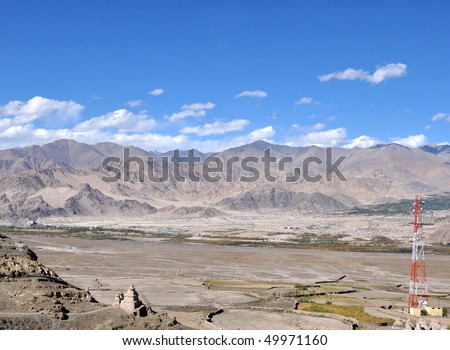wide angle shot of high altitude desert plain with cluster of buildings and telephone tower