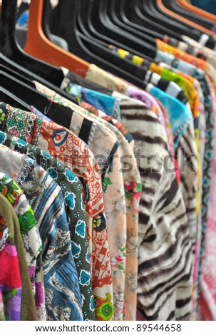 close up of colorful ladies shirt hanging in a row