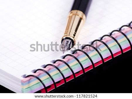notebook and pen isolated in black bakground
