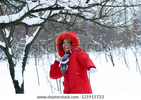 winter girl throwing snowball at camera smiling happy having fun outdoors on snowing winter day playing in snow. Cute playful Caucasian young woman outdoor enjoying first snow.
