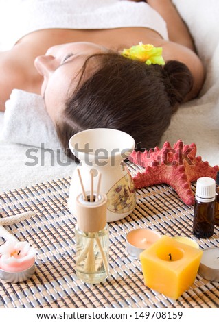 Woman on massage table with oils, essential oils, candles, scents.