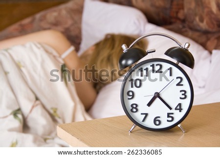 Close up view of table clock and woman sleeping