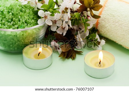 Green sea salt and a lit candle on a green background
