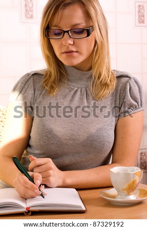 An attractive professional businesswoman, writing notes and jotting down items in a notebook.