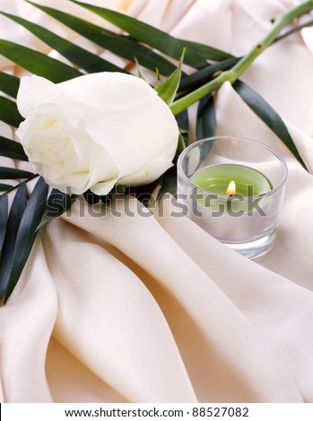 The white rose on a cream silk with a lighted candle