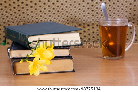 Books to read and a cup of tea with a flower on the table
