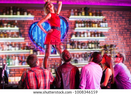 beautiful girl dancing on the bar in a nightclub in the presence of spectators