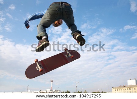 Skater jumps high in air on background blue sky