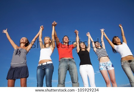 group of happy young people holding hands raised together in the sky
