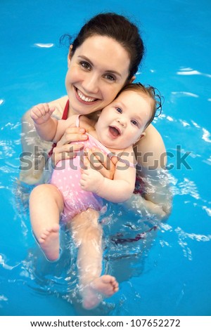 Six month  baby girl at his first swimming lesson with mother