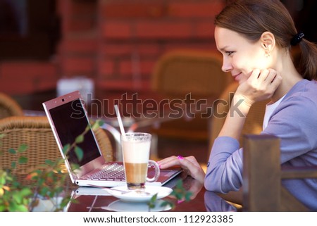 Portrait of successful young woman with laptop in street cafe