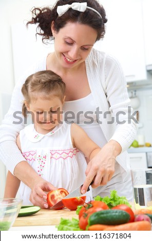 Mother and daughter in kitchen making a salad