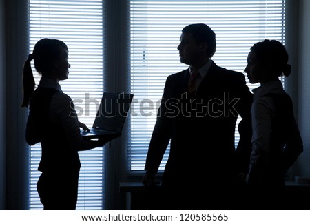 Silhouettes of business team talking on the background of the window in the office