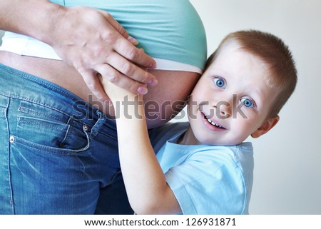 Portrait of happy little boy hugging mother\'s pregnant belly