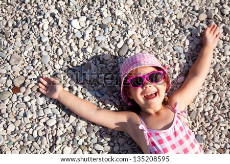 little girl lying on a pebble beach