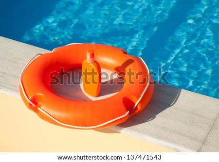 bright orange life preserver floating on the coast swimming pool and sunblock