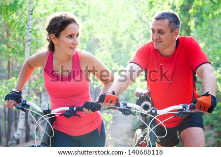 happy mature couple riding a bicycle in the green park