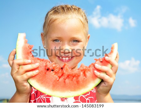 Portrait of cute girl with peace of red watermelon on blue sky background