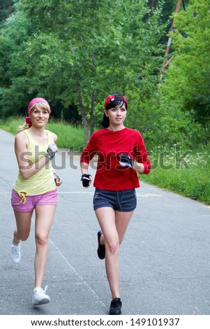 Two young slim women running on the road