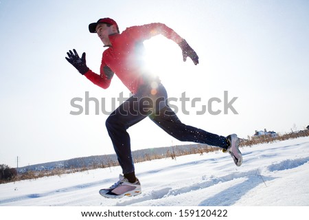 Athletic  man running in winter day on snow