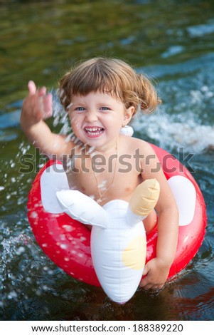 little girl swims in  sea in an red  life preserver