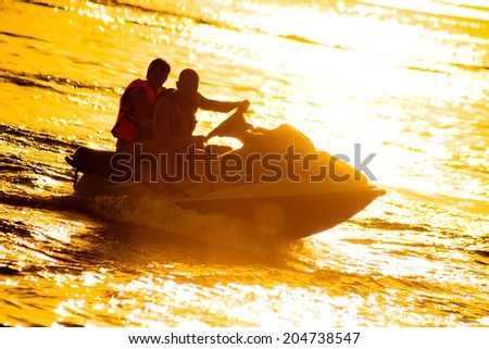 couple drive on the jet ski above the water at sunset .silhouette