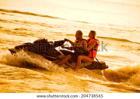 couple drive on the jet ski above the water at sunset .silhouette. spray.