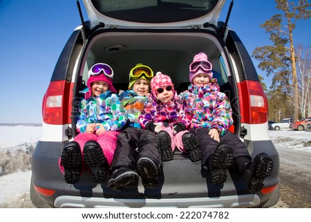 group of kids in winter clothes sitting in the trunk of a car