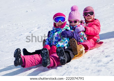 group of kids riding on snow slides in winter time