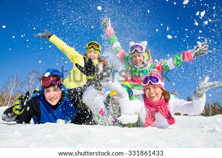 Group of teens playing on snow in ski resort