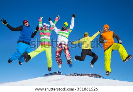 Five friends joyfully jump into the sky over snow drifts in the winter resort