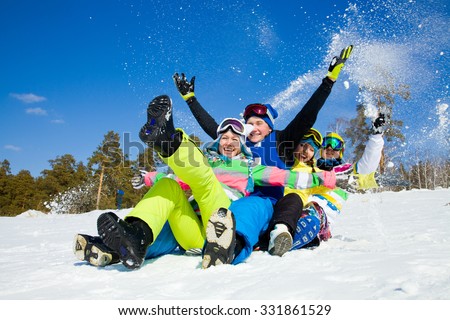 group of funny friends slide downhill together on mountain holiday