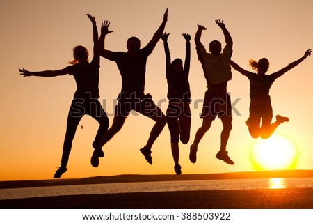 group of happy young people jumping at the beach on  beautiful summer sunset