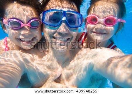 Portrait of a happy dad with two young daughters under water. Selfies