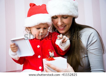 Beautiful mum with a small child open a Christmas gift