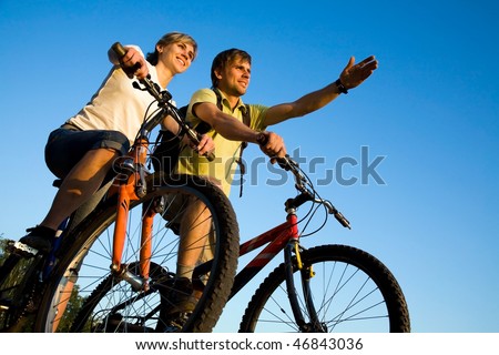 Beautiful Couple on bicycles on the brink of a rock and look afar from rock breakage