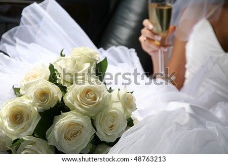 stock photo The bride with a wedding bouquet and champagne in a car