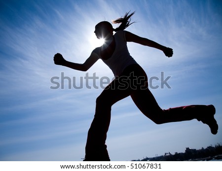Female runner silhouette against the blue sky and sun