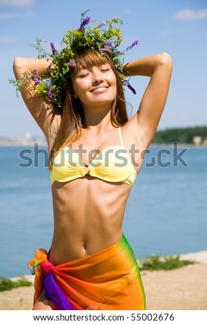 Young beautiful woman enjoy sun day  in a wreath of wild flowers on the sea