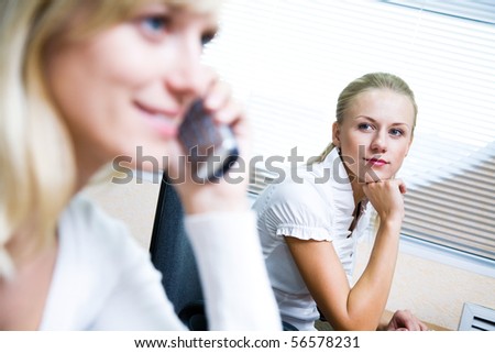 lovely young woman looks at her friend, who is on the phone in the office