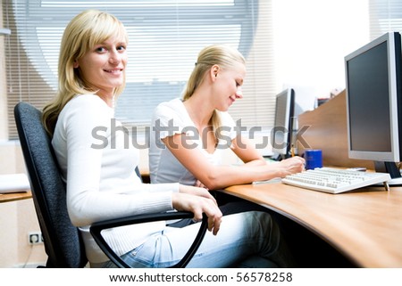 Portrait of beautiful young women sitting on chairs in the workplace for computers