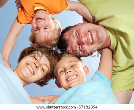 Below view of happy family members looking at camera with smiles background on the blue sky