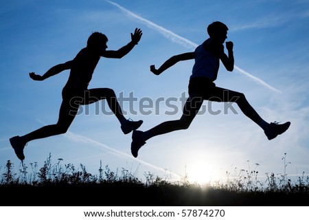 Two men make jog in the field on a sky background by at sunset