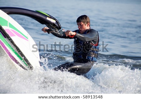 strong man drive on the jetski above the water at sunset . spray.