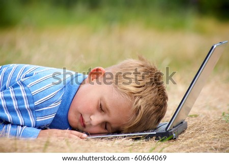 little boy fell asleep on the laptop on  lawn