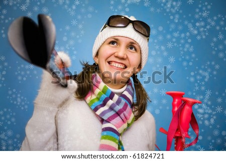 Portrait the beautiful woman in a cap with ski sticks in hands on a blue background