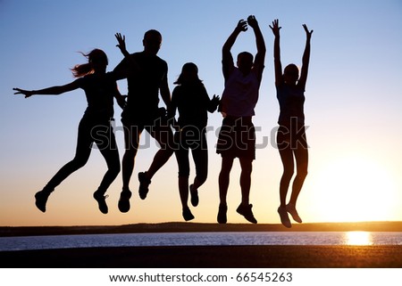 group of happy young people jumping at the beach on beautiful summer sunset