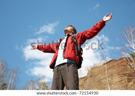 Happy man hiker holding his arms in the air in a feeling of success having reached the summit