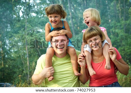 family lifestyle portrait of a mum and dad with their children having good time in the green  park